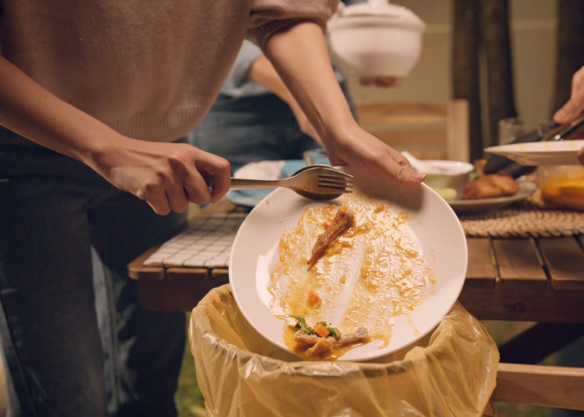 voedselverspilling Spanje: iemand gooit bord eten leeg in prullenbak na een feestje