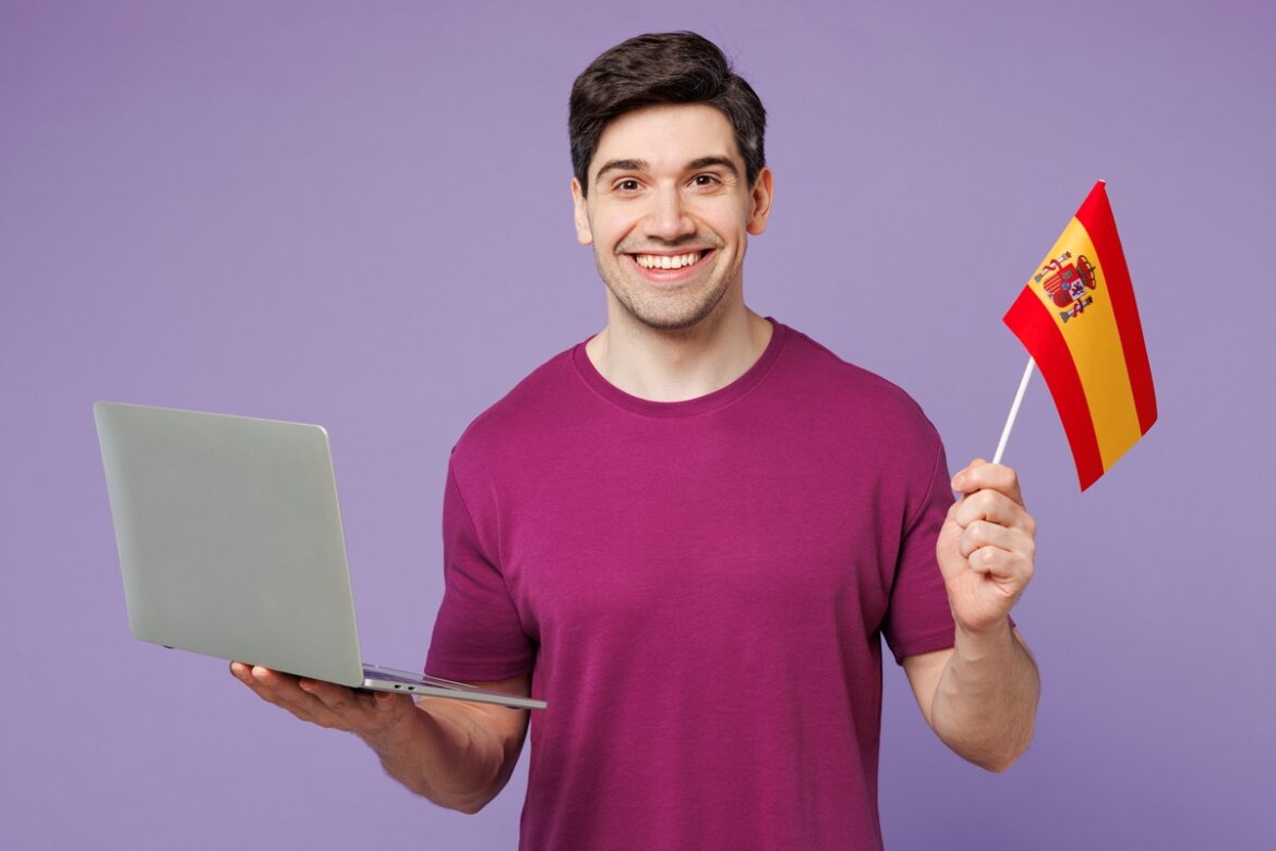 Man met Spaanse vlag en laptop in hand: Werken in Spanje