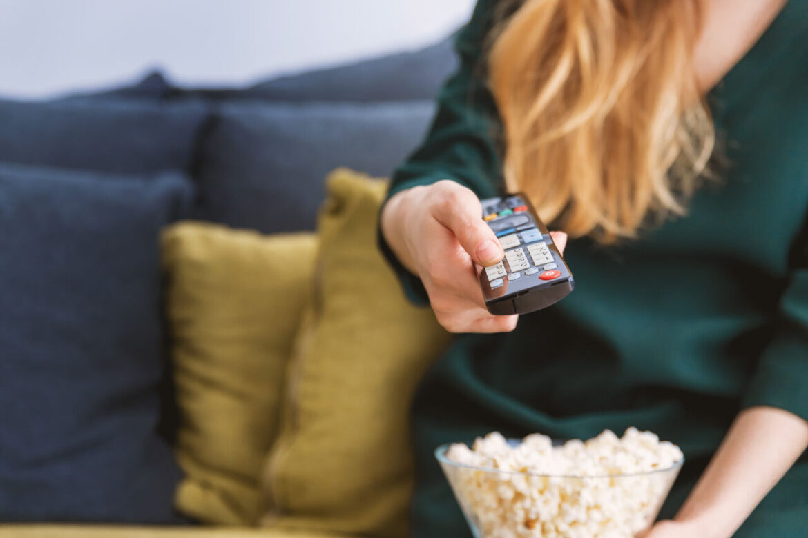 Vrouw met afstandsbediening kijkt naar Spaanse televisie om Spaans te leren met Spaanse tv-programma's.