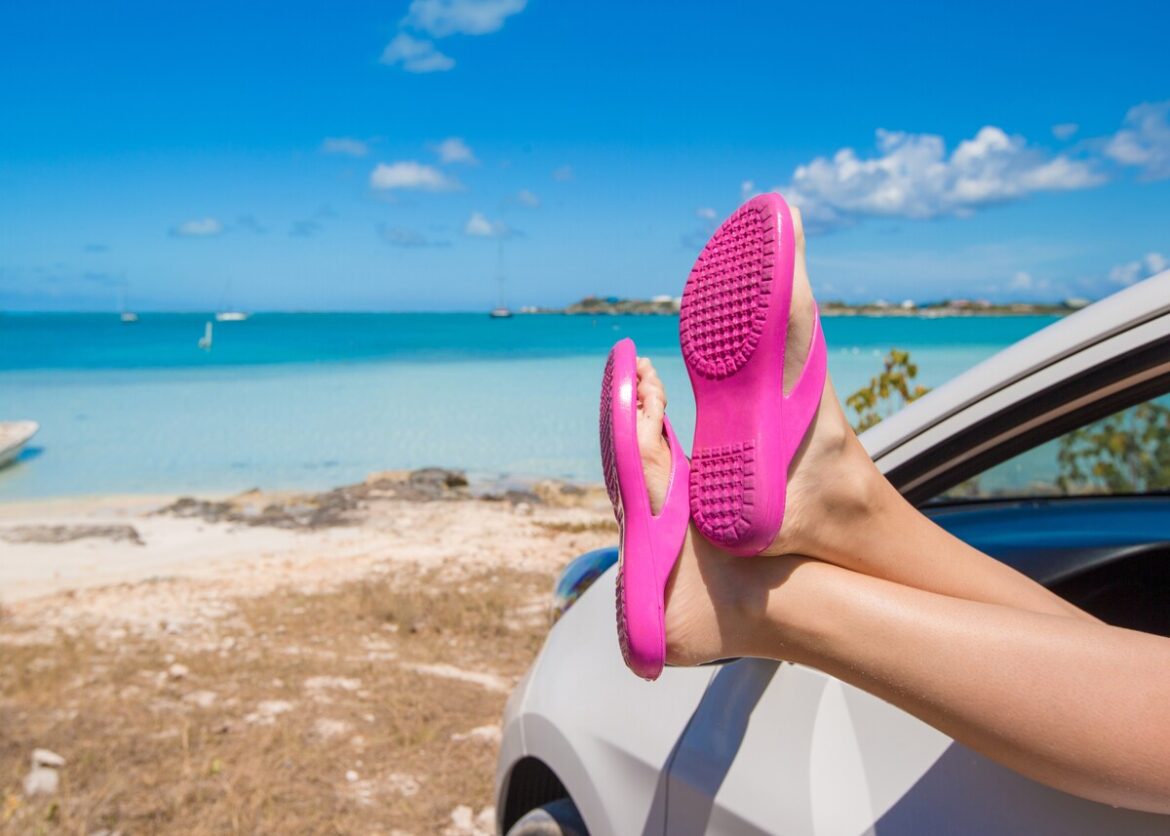 vrouwenbenen met slippers aan voeten steken uit autoraam: mag je autorijden op slippers in Spanje?