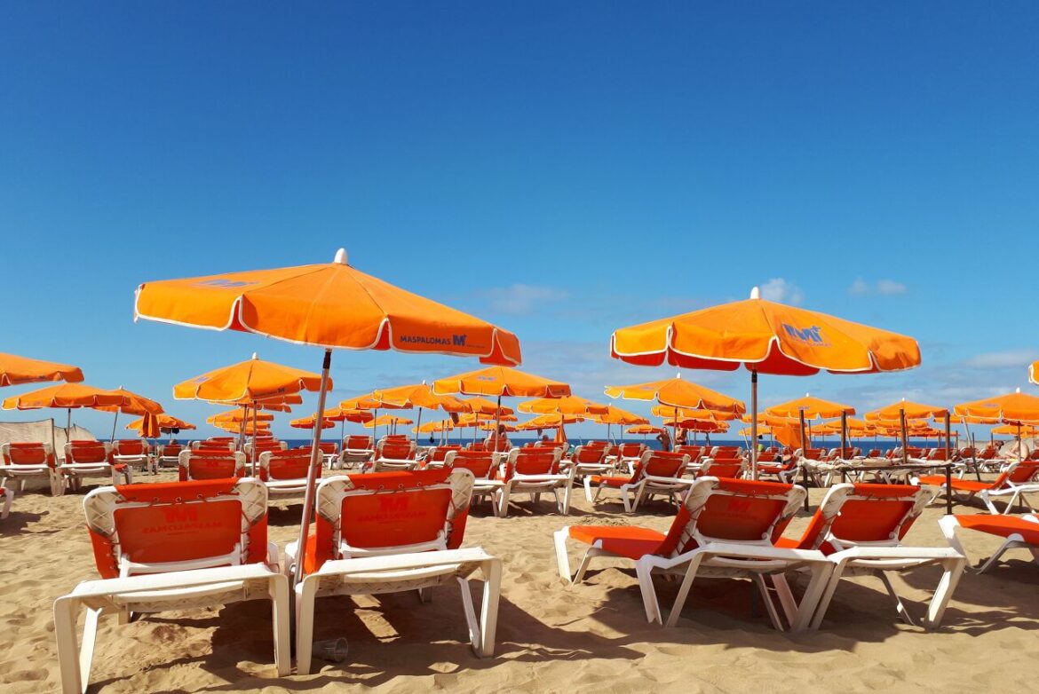 Oranje zonnebedden en parasols op het strand van Maspalomas, een populaire toeristische bestemming in Spanje.