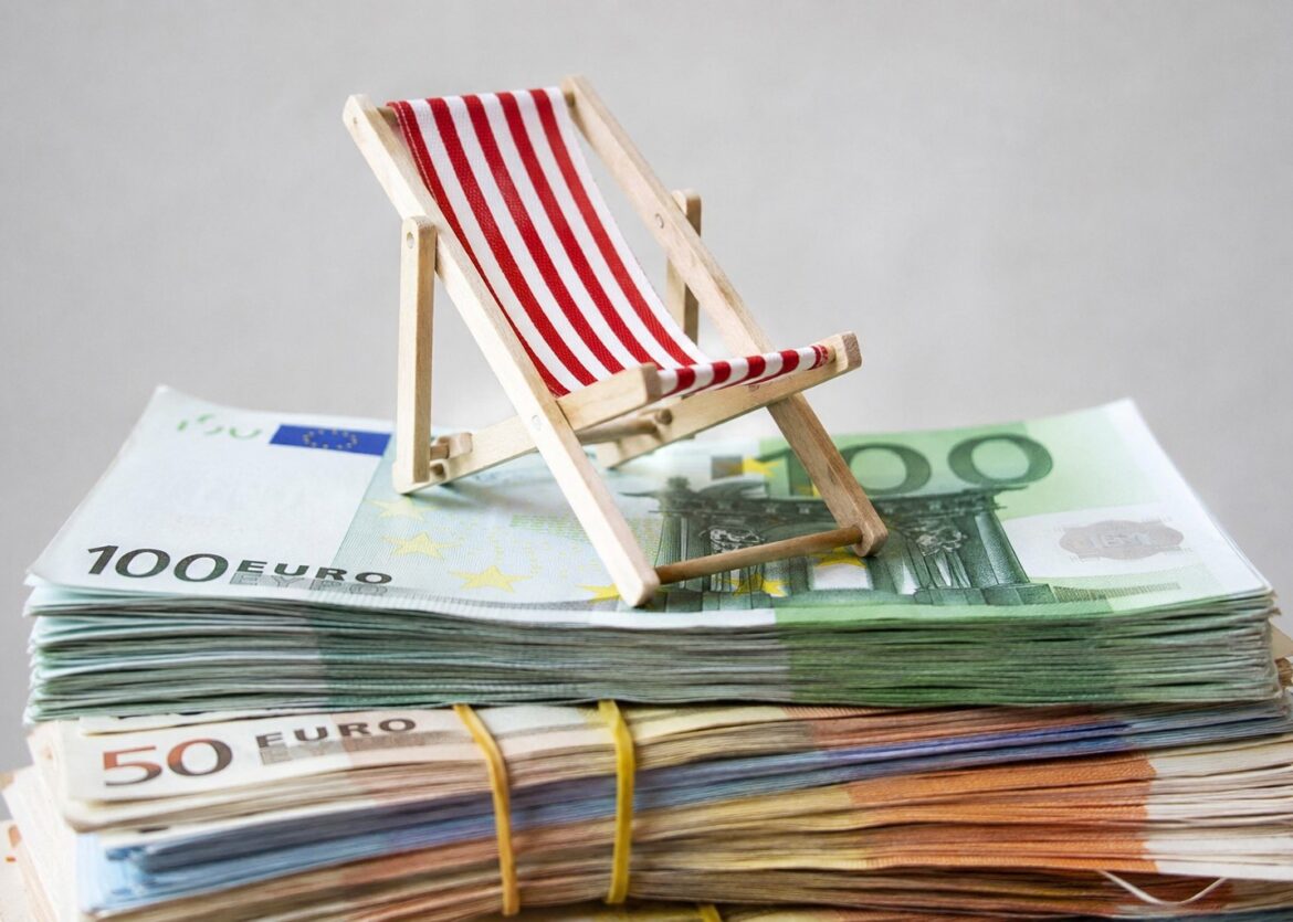 een stapel bankbiljetten met daarop een strandstoel: steeds meer mensen lenen geld om op vakantie te gaan
