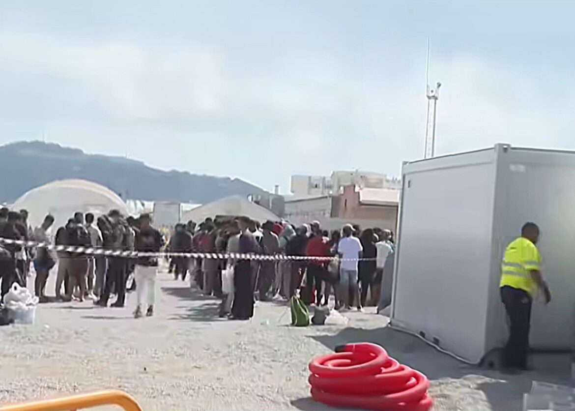 migranten wachten op hun beurt om naar het kamp in de haven van Ceuta te worden overgebracht